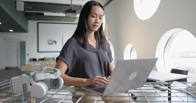 Young Adult Businesswoman Focusing on Laptop in Modern Open plan Workspace