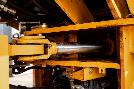Heavy machinery hydraulic ram with exposed piston rod and articulated mounting joint, representing force transmission components for construction equipment servicing