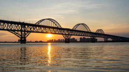 Fototapeta premium Steel arch bridge over river at sunset,Jiujiang China