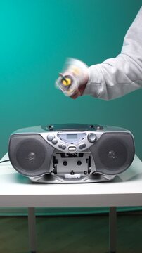 Vertical video hand holding clear retro cassette with a pencil rewinding tape above vintage silver boombox, evoking analog music nostalgia