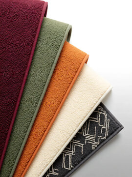 Close-up of stacked colorful carpet and rug texture samples isolated on white background