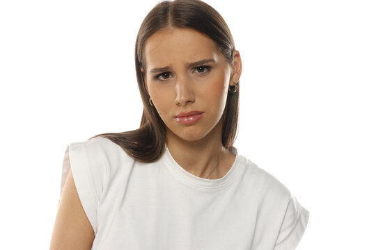 Portrait of a dissatisfied woman frowning, makeup, on white background.