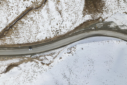 Aerial top view of a car driving  in frozen road