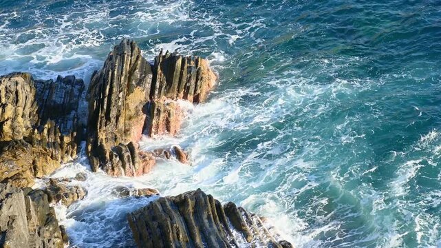 Ocean waves crashing against rocky coastal cliffs, view from above