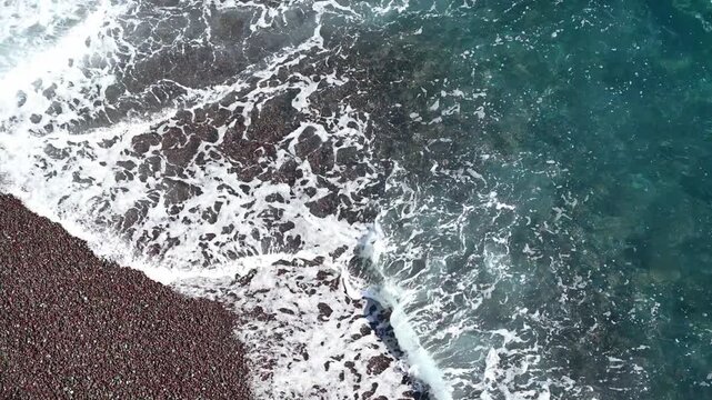 Waves washing onto pebble beach and rocky shoreline from above