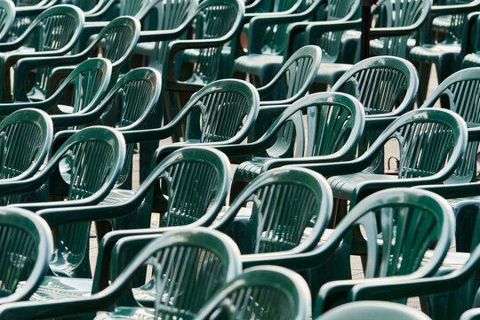 Rows of empty green plastic chairs arranged for a public event or community gathering, creating a visual concept of participation, belonging, social connection, audience and collective activities.