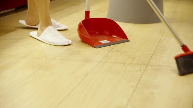 Cleaner Sweeping Wooden Laminate Floor Surface With Brush And Red Dustpan. Housekeeping. Home Hygiene Maintenance 