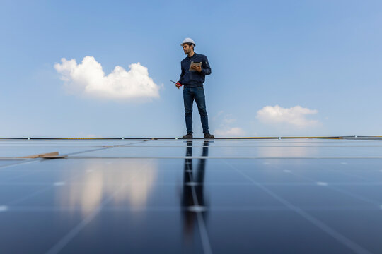 Engineer service check installation solar cell on the roof of factory. Engineers walking on roof inspect and check solar cell panel. Engineer working inspection installation solar cell on the roof