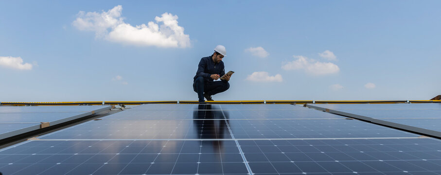 Engineer service check installation solar cell on the roof of factory. Engineers walking on roof inspect and check solar cell panel. Engineer working inspection installation solar cell on the roof