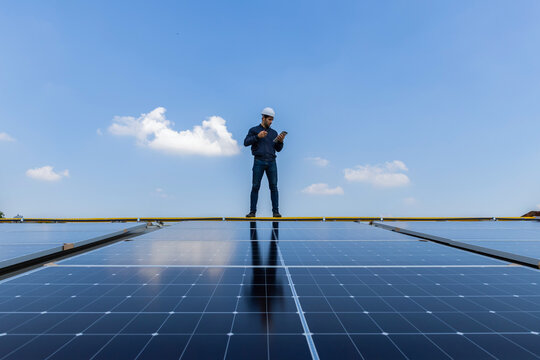 Engineer service check installation solar cell on the roof of factory. Engineers walking on roof inspect and check solar cell panel. Engineer working inspection installation solar cell on the roof