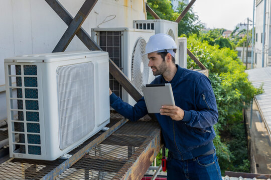 Air conditioner repairman, technician checking air conditioner, measuring device for refilling air conditioner. HVAC service technician using gauges to check refrigerant and add refrigerant.