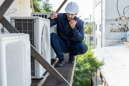 Air conditioner repairman, technician checking air conditioner, measuring device for refilling air conditioner. HVAC service technician using gauges to check refrigerant and add refrigerant.