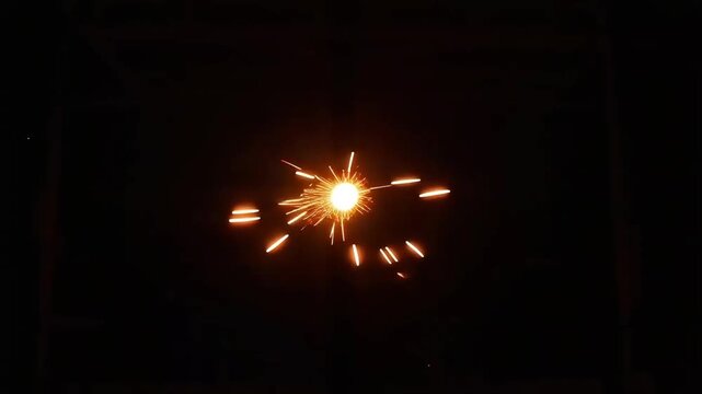Spinning fire sparks forming a vibrant circular vortex motion against a dark night background, abstract light painting effect.