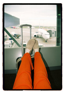Legs propped on a suitcase at the airport departure gate