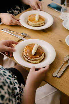 Table set with buttered pancakes and syrup in minimalist cafe