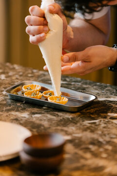 Chef using pastry bag to fill tartlets in fine restaurant.
