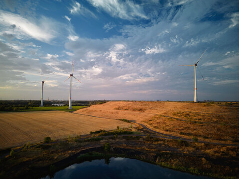 Wind Turbines Stand in a Field Under a Cloudy Sky in the Evening