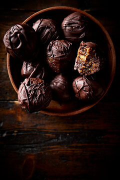 Chocolate Covered Date and Pistachio Energy Balls in Wooden Bowl on Dark Rustic Background
