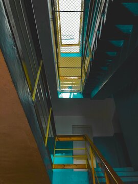 Low angle interior view of an old apartment building staircase with blue walls.