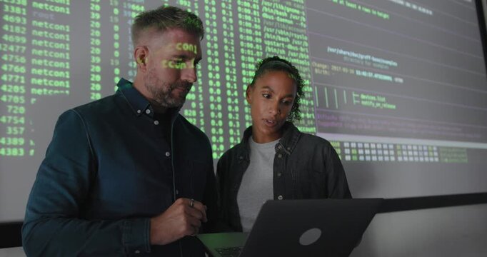 Co-Workers Reviewing Data Presentation Together, using Laptop and Projection Screen in Office
