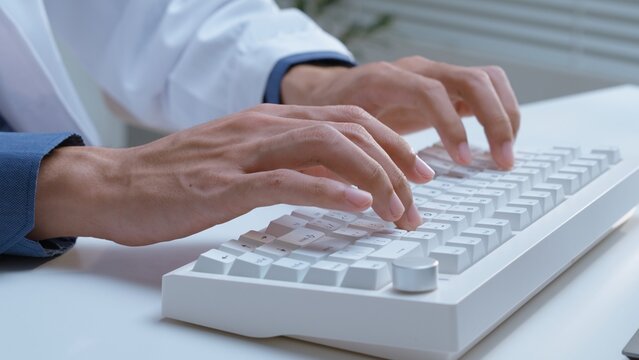 Healthcare professional typing on computer keyboard in medical office, representing digital documentation, patient data entry, healthcare administration, clinical records and modern hospital workflow.