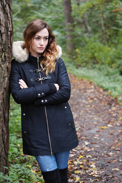 Woman leaning against tree in autumn forest looking sad lonely and depressed