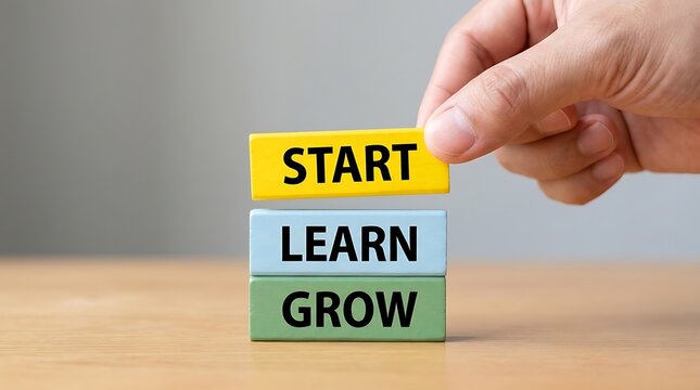 A hand places a yellow block with the word start on top of blue learn and green grow blocks, symbolizing progress and personal development stages for success.