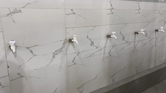 Row of Water Faucets on White Marble Ceramic Wall Background