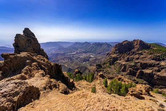 Dramatic volcanic mountain landscape in Gran Canaria, Canary Islands, with rugged rock formations, deep valleys and a clear blue sky.