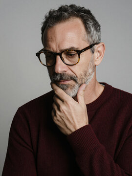 Thoughtful mature businessman touching beard in deep contemplation