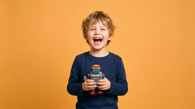 Joyful young boy with a vintage wind-up robot toy against an orange background