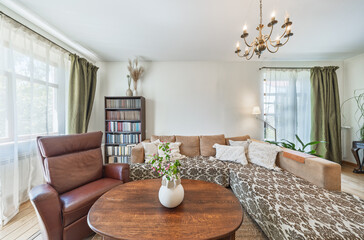 Cozy Living Room Interior With Sectional Sofa, Leather Armchair, Wooden Coffee Table And Bookcase © Mindaugas Dulinskas