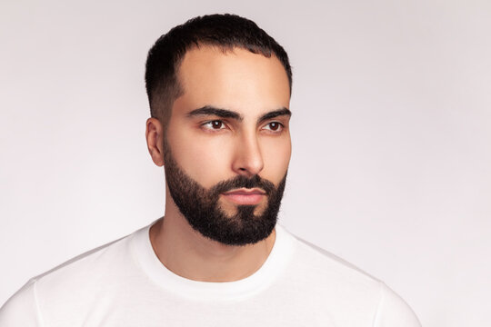 Male model wearing white t-shirt turning head showing strong jawline and perfect beard fade trim professional skin aesthetic appearance result isolated over gray background