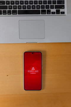 Vertical top view of smartphone with security alert beside laptop