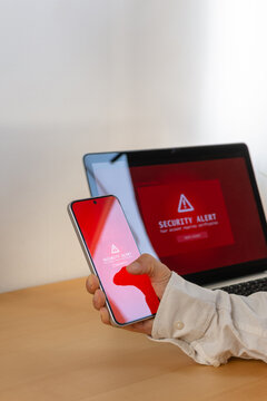 Vertical close up of smartphone with security alert and laptop