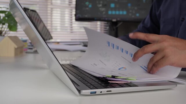 Business professional checking and reading business financial reports with colorful binder clips at office desk, concept of corporate work, document analysis, management, and administration.