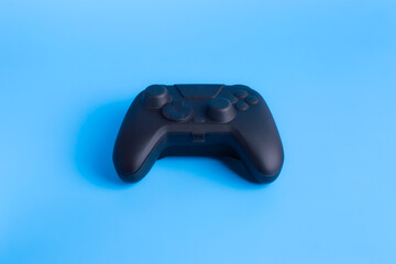 Front view of black wireless gamepad controller on solid blue background. Clean concept for gaming mockups, esports, and technology advertising.  © wibiwisnu