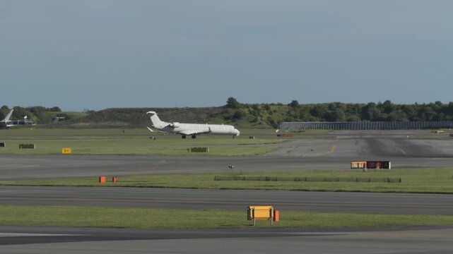 Wide shot of white commercial airplane parked on airport runway