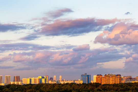 dark pink clouds in blue sunset sky over city