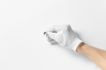a hand in a white woven glove holding a ring with a stone on the white background