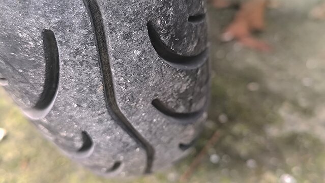 Extreme close-up of a textured black motorcycle tire showing detailed tread patterns, grooves, and surface texture