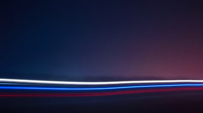 Long exposure light trails in white, blue, and red colors against a dark background