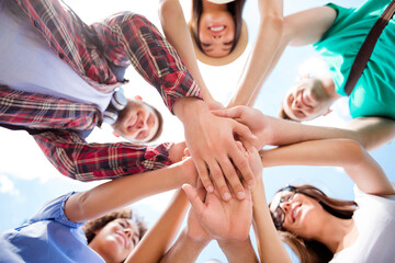 Obraz premium Young friends stacking hands in a circle showing teamwork, unity and friendship during an outdoor summer gathering and celebration