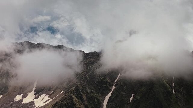 Dense clouds drift across rugged high mountain peaks