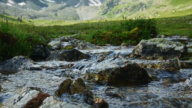 Clear mountain stream flowing over rocks in valley