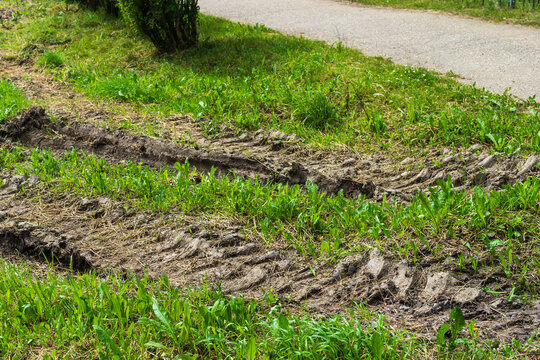 Heavy vehicle tire ruts tear up grass in urban green space