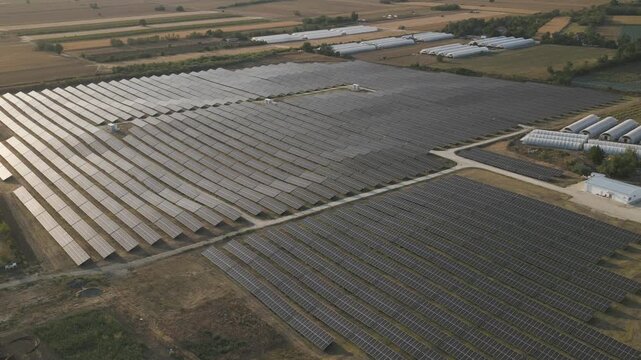Renewable energy and sustainability concept, aerial drone view of a large solar farm with photovoltaic panels in a rural landscape, clean energy power