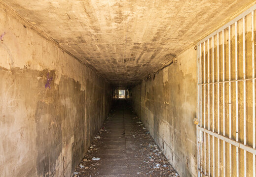 Rusty Barred Gate Beside a Dark Concrete Tunnel