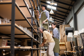 A diverse team works together in a storage warehouse, organizing inventory on tall metal shelves...