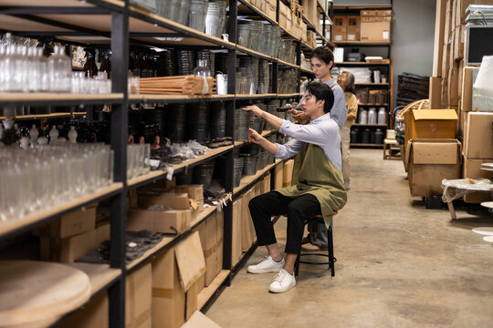 Family business worker organizing craft and ceramic merchandise inside the warehouse while checking inventory stock levels for wholesale retail distribution and supply chain management